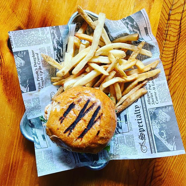 A burger and french fries on a plate on a wooden table.